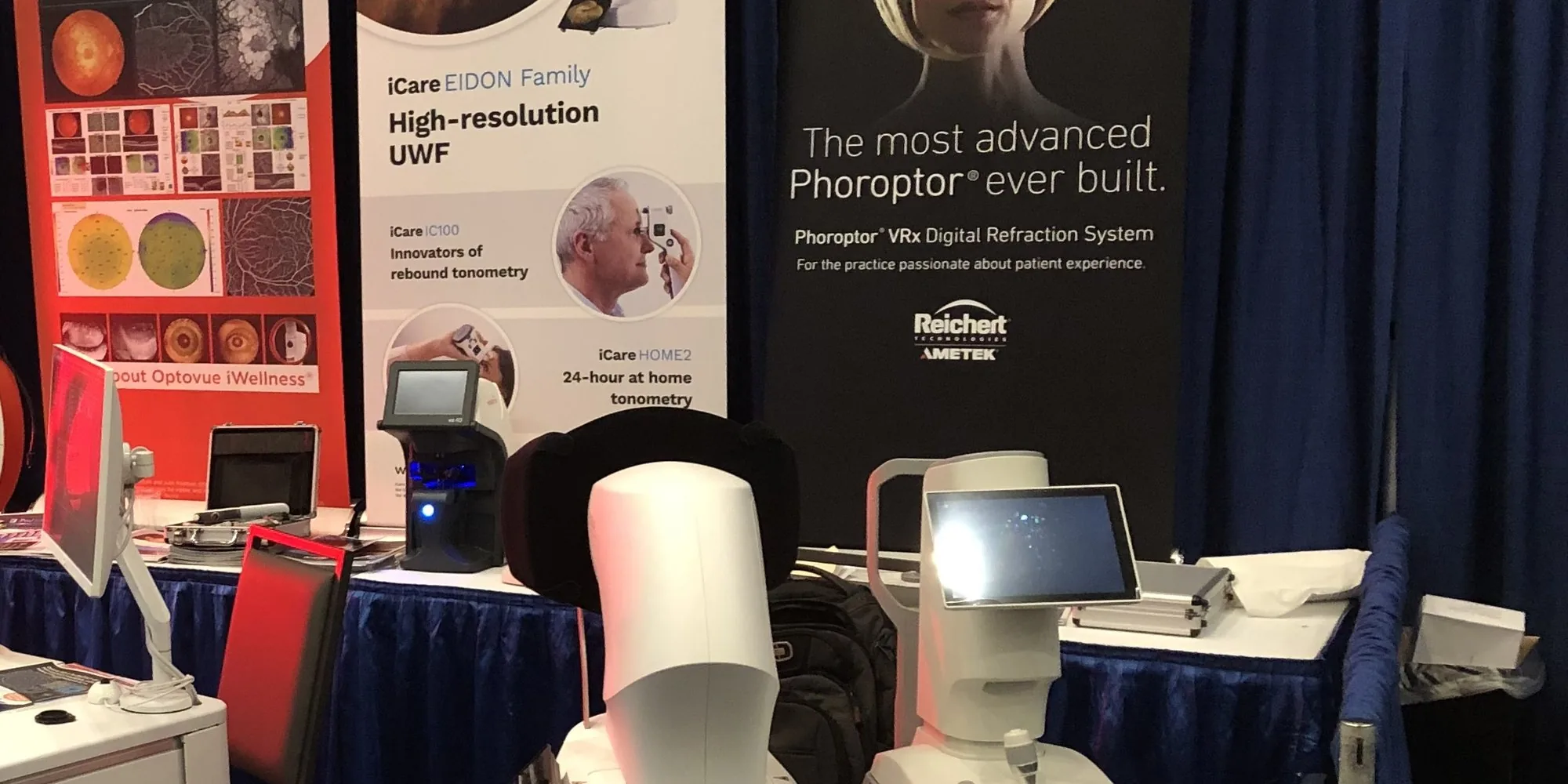 Carolina Optics booth at an ophthalmic trade show showing iCare EIDON, Optovue Solix, and Reichert Phoroptor VRx